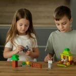 Kreatywne zabawy na deszczowe dni: rozwój wyobraźni bez telewizora i smartfona Dwoje dzieci układa zabawki na drewnianym stole rozwijając wyobraźnię