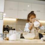 Dziewczynka w kuchni wlewa mleko, przygotowując domowe wypieki