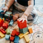Małe dziecko bawi się kolorowymi klockami na dywanie