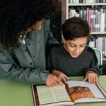 Nauczycielka czyta książkę z przedszkolakiem w przytulnej bibliotece