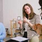 Psycholożka rozmawia z parą w jasnym gabinecie, trzymając notatnik