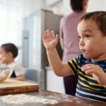 Dwoje małych dzieci wspólnie piecze w kuchni, ucząc się przez zabawę
