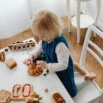 Dwulatek bawi się przy stoliku edukacyjnymi zabawkami Montessori