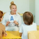 Nauczycielka pokazuje literę przedszkolakom podczas zajęć w sali