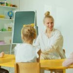 Nauczycielka rozmawia z przedszkolakami w kolorowej sali zajęć