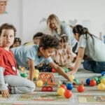 Dzieci bawiące się i uczą przy stolikach w kolorowym przedszkolu