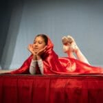 Dziewczynka w stroju Czerwonego Kapturka leży na scenie podczas występu