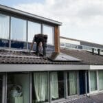 Technik montuje panele fotowoltaiczne na dachu domu jednorodzinnego