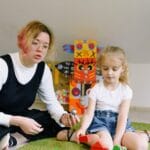 Nauczycielka bawi się z przedszkolakiem kolorowymi klockami w sali