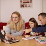 Rodzice z dzieckiem uczą się przy laptopie w domu
