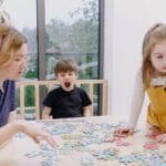 Rodzina układająca puzzle przy stole w domu