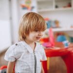 Uśmiechnięte dziecko bawi się w kolorowej sali przedszkolnej