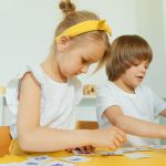Dwoje dzieci podczas zabawy edukacyjnej z literami w sali przedszkolnej